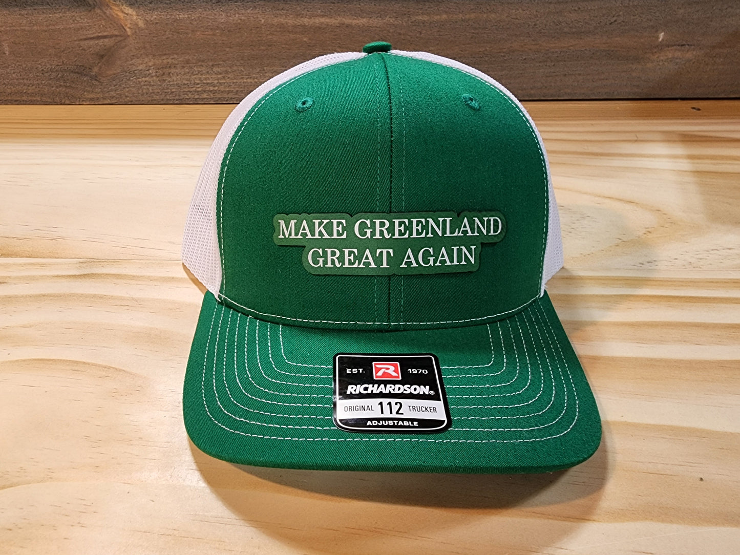 "Make Greenland Great Again" hat in green displayed on a wooden surface.