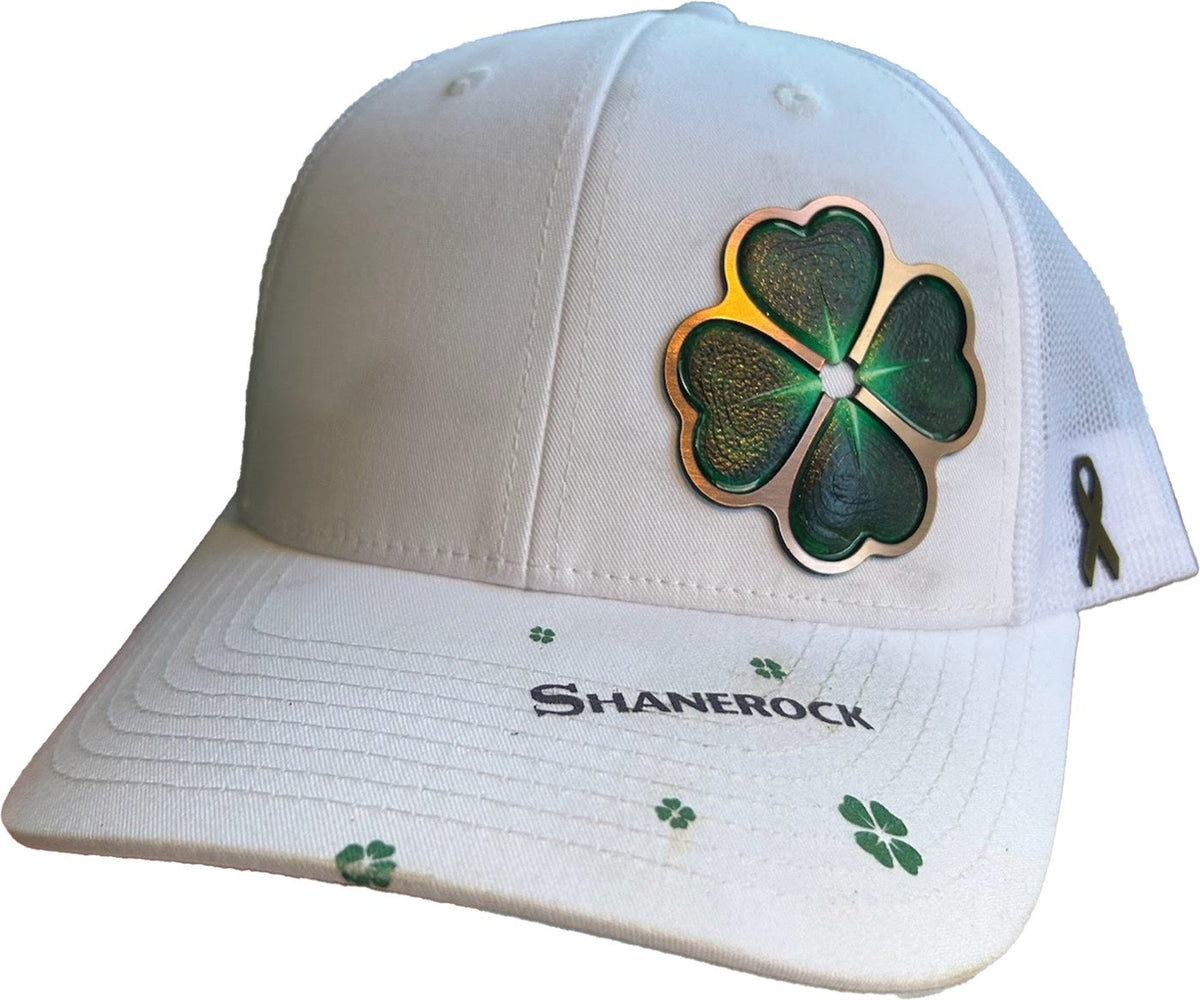 The Shanerock hat: a white trucker with a green four-heart clover edged in copper, SHANEROCK and small green clovers on the bill, and a gold ribbon on the side mesh