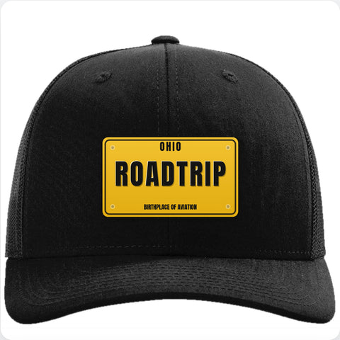 Black Richardson 112 trucker hat with a vintage gold license plate patch reading ROADTRIP.
