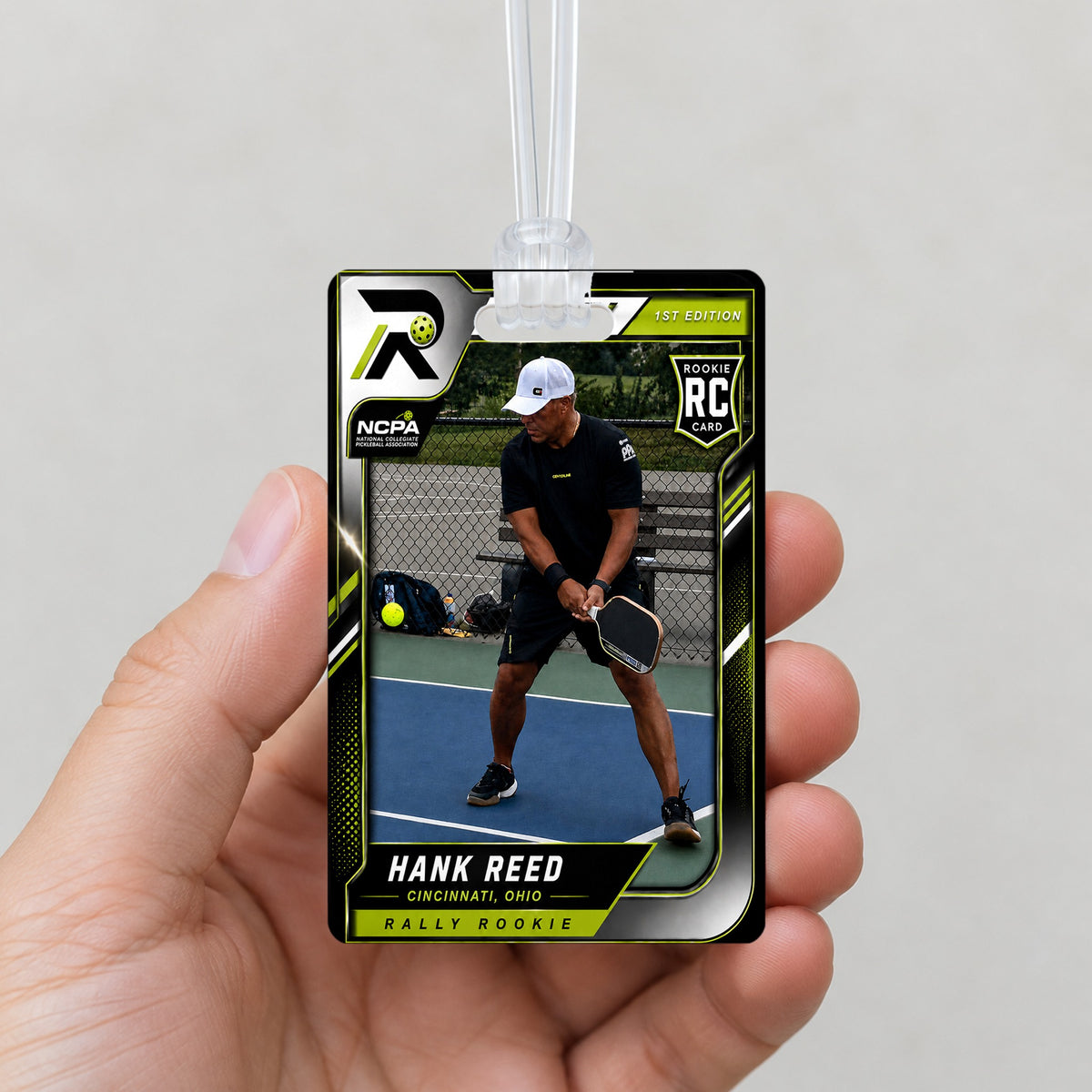 Rally bag tag held in a hand for size, two-sided acrylic with the player's Rally card and clear loop