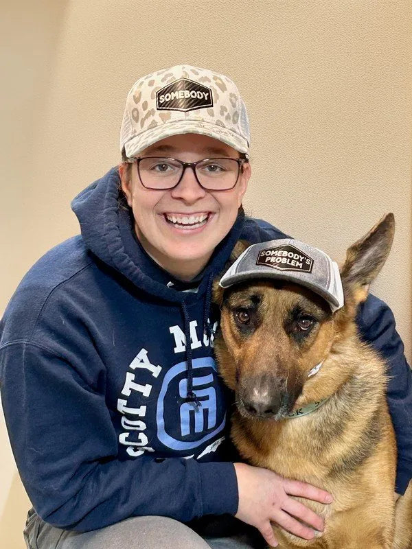 A woman and her German Shepherd wearing matching trucker hats