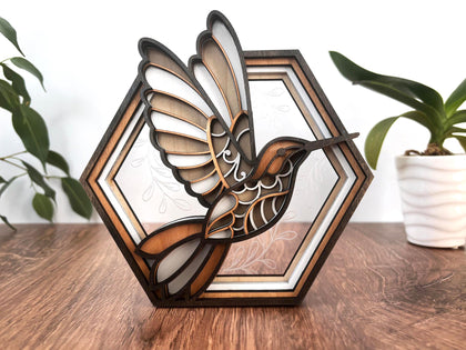 Layered wood hummingbird in a hexagon frame on a table