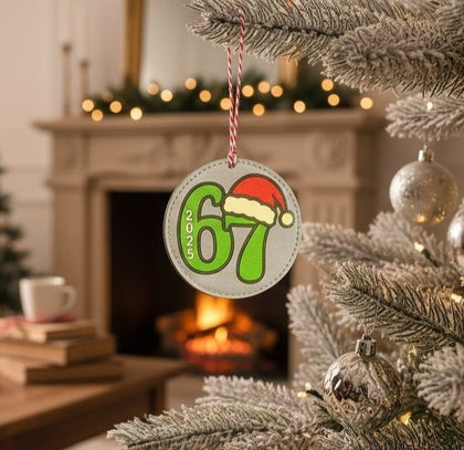 Round ornament with a green 67 in a Santa hat, hanging on a Christmas tree