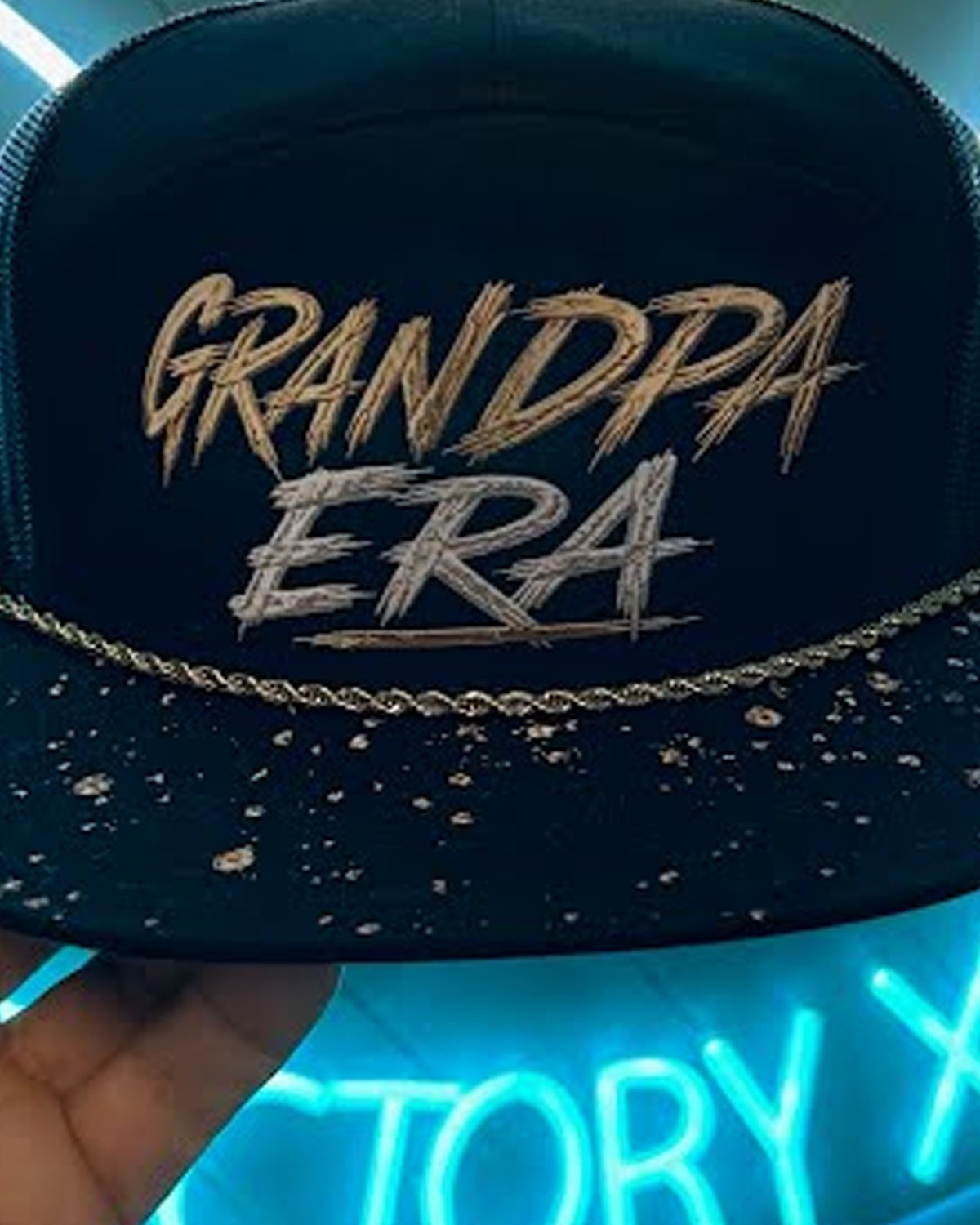 A GRANDPA ERA hat we made as a gift: black trucker cap with raised gold and silver lettering, a gold chain across the front and a gold-splattered brim