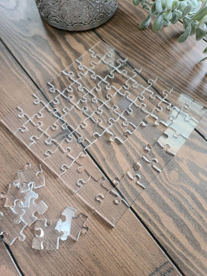 Clear acrylic puzzle pieces scattered on a wood table