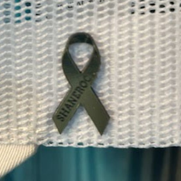 A flat ribbon-shaped patch engraved SHANEROCK, sitting flush on a white waffle-knit hat