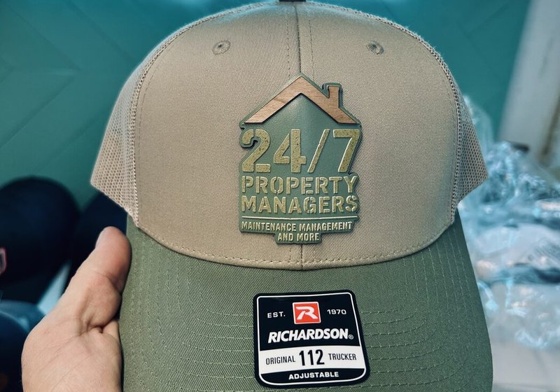 Olive and khaki 24/7 Property Managers trucker cap with raised, dimensional lettering under a house outline